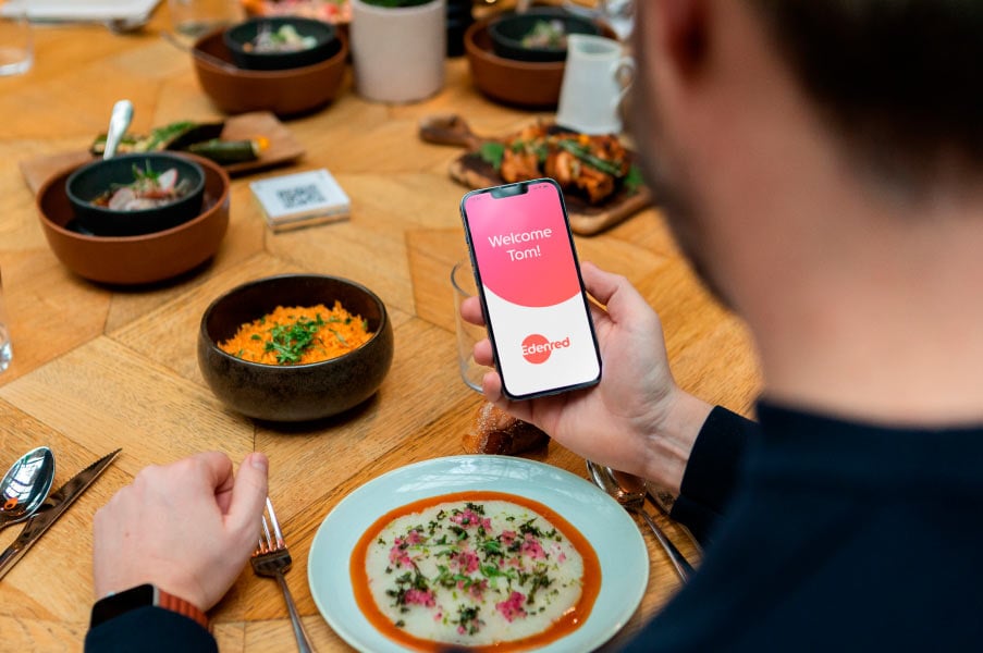 Beneficiario desayunando con telefono en mano